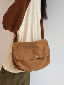 Brown canvas messenger bag for women featuring a large flap and metallic button