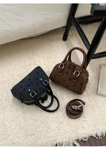 Detailed top view of polka dot woven mini boston bags in black and brown finishes
