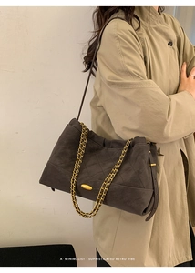 Close-up of retro quilted shoulder bag with gold chain strap on minimalist beige coat