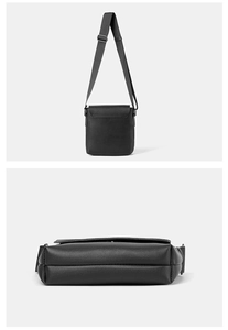 Detail view of black textured leather crossbody bag with adjustable strap and square flap
