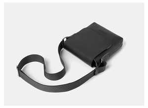 Close-up of matte black grain texture messenger bag with embossed logo and wide strap