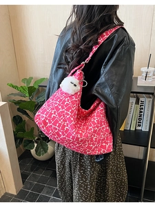 Detail of hobo bag in pink spot pattern featuring a white plush toy charm on the strap