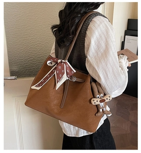 Detail of brown tote bag with decorative floral scarf and rabbit plush charm accessory