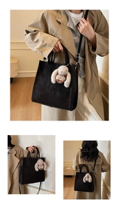 Detail of black suede tote bag with plush rabbit charm and adjustable shoulder strap