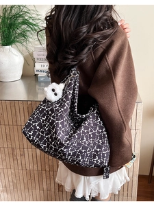 Detailed view of hobo bag with abstract floral print and plush monster charm decoration