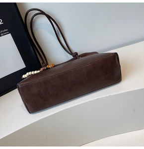 Détail du sac cabas en cuir vintage marron foncé avec pompon ethnique perlé