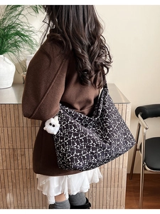 Detail of canvas bucket bag with star pattern and plush charm on female model