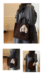 Detail of dark brown PU leather tote bag featuring a cute plush bunny charm and shoulder strap