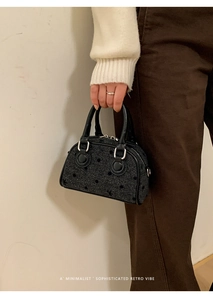 Close-up of retro gray tweed baguette bag with black polka dots and leather handles