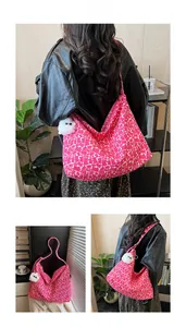 Detailed view of magenta hobo bag with plush pendant on a model in a cozy setting