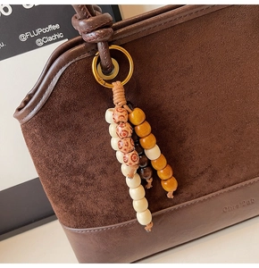 Détail du sac cabas en daim vintage avec perles décoratives en bois et texture cuir
