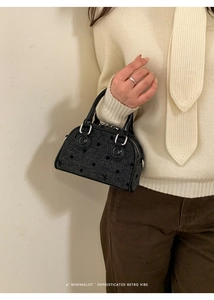 Detail of a black mini Boston bag with textured jacquard stars and leather handles