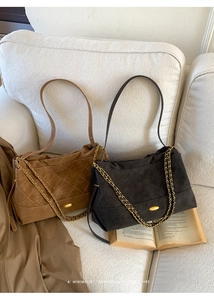 Detailed view of caramel and grey quilted suede tote bags with golden chain straps