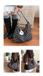 Detail view of large tote bag with black and white abstract patterns and white fluffy charm