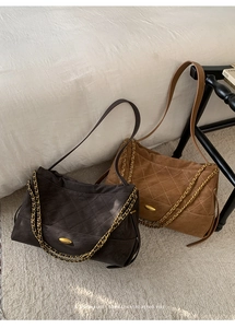 Close-up of quilted suede hobo bags with golden chain straps and oval metal buckles