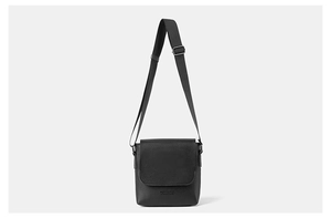 Detailed view of black synthetic leather texture and logo embossing on flap crossbody bag