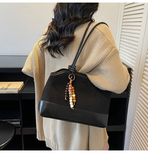 Détail d'un sac cabas vintage en daim noir avec patchwork de cuir et pendentif à glands