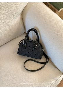 Close-up of black polka dot woven texture handbag on a soft beige fleece sofa
