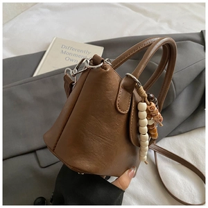 Détail d'un sac à main vintage en cuir marron avec breloque perlée sur un blazer