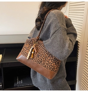 Détail d'un sac cabas vintage avec imprimé léopard et pompon en perles de bois colorées