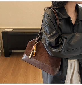 Détail de la texture en daim et cuir sur un sac cabas marron foncé avec charm en perles