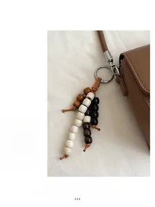 Detail eines hölzernen Perlenanhängers mit Silberverschluss an einer Lederhandtasche