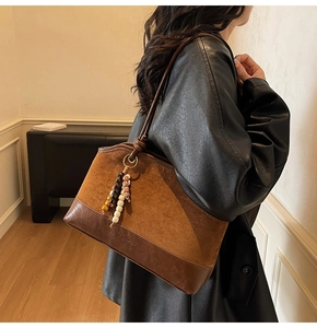 Détail du sac cabas marron vintage bi-matière avec pendentif perlé et logo gravé