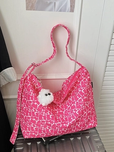 Pink and white cat-patterned canvas crossbody bag with a plush charm on a silver suitcase