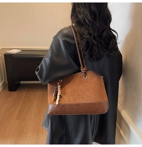 Détail du sac cabas marron vintage avec pendentif ethnique et mélange de cuir