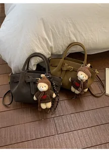 Detail of retro leather handbags in brown and khaki with cute teddy bear charms