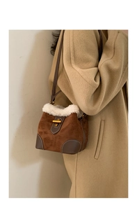 Détail du sac seau en daim marron avec bordure en polaire blanche et boucle dorée