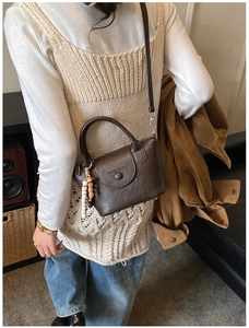 Détail du sac à main vintage marron foncé en similicuir avec breloque et poignée haute