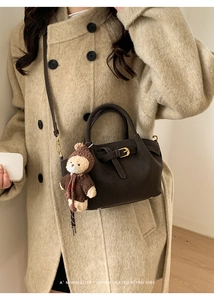 Detail of dark brown retro leather handbag with gold buckle and teddy bear charm