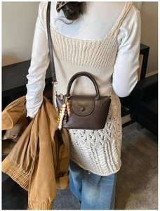 Détail d'un sac à main vintage en cuir marron foncé avec des perles en bois sur la bandoulière