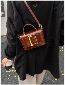 Close-up of retro caramel brown leather handbag with large gold square buckle detail