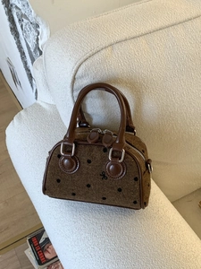 Brown polka dot mini Boston bag with bow embroidery and leather trim on a cozy sofa