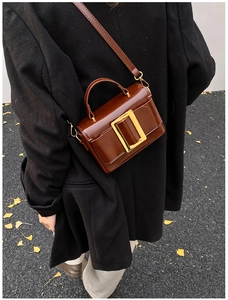 Detail of vintage brown leather handbag with oversized gold buckle and adjustable strap