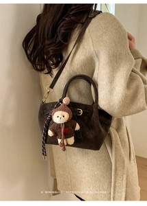 Retro brown suede handbag with cute bear charm and gold buckles in a minimalist style