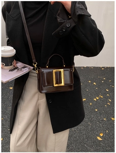 Detail of dark brown retro shoulder bag with a large golden square buckle for women