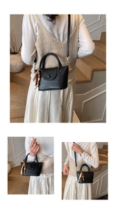 Détail du mini sac bandoulière noir avec un pendentif unique en perles de bois