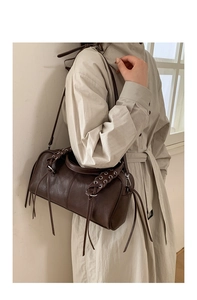 Detailed view of woven leather texture and long tassels on a vintage dark brown bag