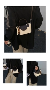 Détail du sac à main bicolore en cuir avec pompon en perles de bois et bandoulière longue