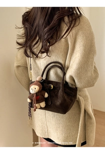 Detailed back view of a dark brown matte retro shoulder bag with a cute bear charm