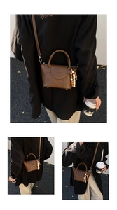Détail du sac à main marron foncé avec breloque perlée et texte mode embossé