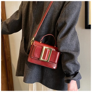 Chic burgundy square handbag with large gold buckle detail on a tweed coat outfit