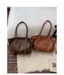 Detail view of large retro tote bags in dark brown and caramel with metal eyelet straps