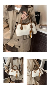 Détail du sac à main tressé beige avec bordure en cuir marron et breloque en perles