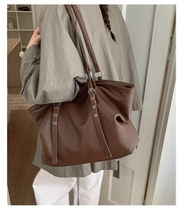 Detail of dark brown tote bag showing lychee pattern leather and metallic eyelets