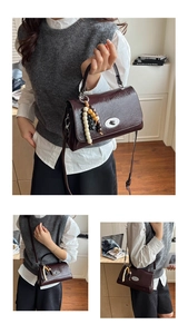 Details der burgunderroten Ledertasche mit Silberverschluss und dekorativem Perlenanhänger