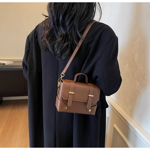 Rear view of model wearing a vintage brown leather crossbody bag over a black winter coat